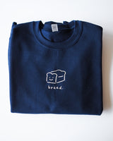 Navy blue Gildan sweater with bread embroidery folded up