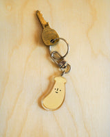 Banana with a cute smile acrylic keychain attached to a key displayed on a wooden surface