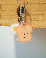 Bread and egg with a cute smile acrylic keychain attached to a key